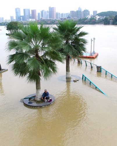 4月11日，市民在柳江邊被洪水淹沒的平臺上垂釣。