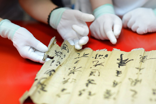 2013年7月15日，在天津博物館，2013年全國紙質文物保護修復技術培訓班學員在專家指導下展開受損的古舊字畫。