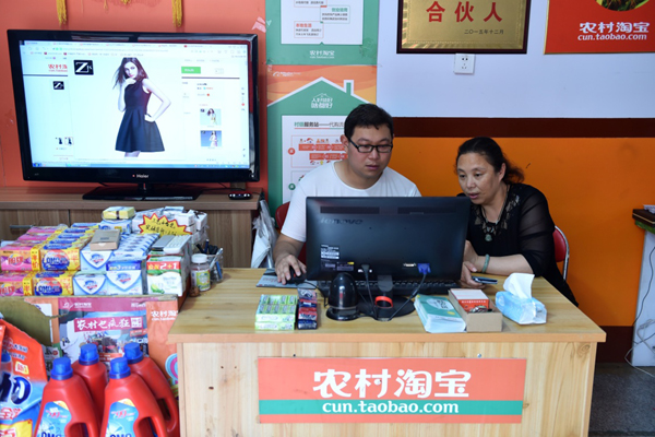 在山西省侯馬市垤上村農村淘寶服務站，43歲的馬巧鈴（右）在農村淘寶合夥人馬永亮的幫助下網購衣服（6月1日攝）。新華社記者 詹彥 攝