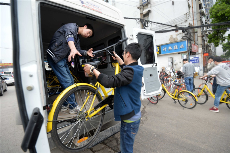 在武漢市光谷廣場附近一馬路邊，共享單車企業工作人員清理轉運佔道車輛（4月3日攝）。