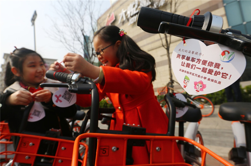 天津市和平區萬全小學學生為共享單車繫上溫馨提示，呼籲市民愛護共享單車，文明出行（3月21日攝）。