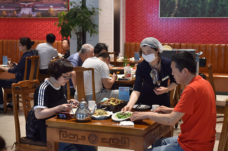 5月2日,马凯餐厅(地安门店)内,服务员戴著口罩给客人上菜.